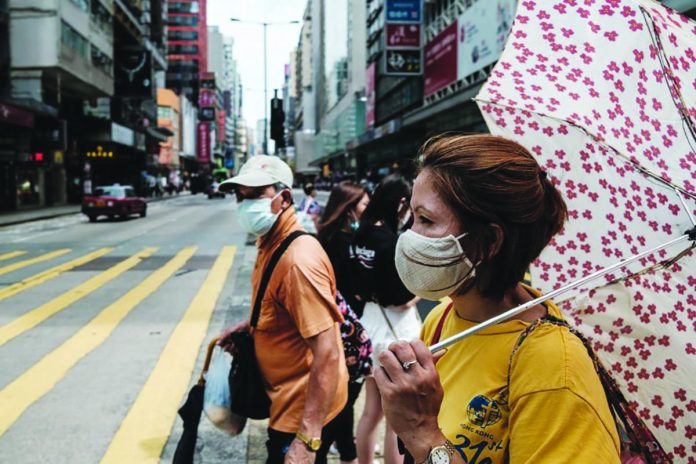 pedestrians prepare to walk across a main road in hk Pedestrians prepare to walk across a main road in Hong Kong on July 20, 2020. AFP