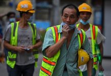 Chinese workers wear facemasks leave the construction a at the end of their in Colombo on March 25, 2020.China faced demands on Thursday to explain why a state-backed firm claimed it had vaccinated dozens of staff against the coronavirus before sending them back to work at a mine in Papua New Guinea. (AFP/Ishara S. Kodikara )