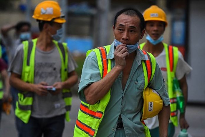 Chinese workers wear facemasks leave the construction a at the end of their in Colombo on March 25, 2020.China faced demands on Thursday to explain why a state-backed firm claimed it had vaccinated dozens of staff against the coronavirus before sending them back to work at a mine in Papua New Guinea. (AFP/Ishara S. Kodikara )