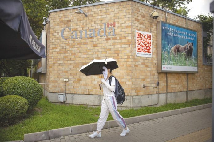 A woman wearing a face mask to help protect against the coronavirus walks past the Canadian Embassy in Beijing, Thursday, Aug. 6, 2020. AP A woman wearing a face mask to help protect against the coronavirus walks past the Canadian Embassy in Beijing, Thursday, Aug. 6, 2020. AP