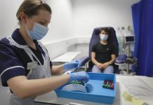Clinical Research Nurse Aneta Gupta labels blood samples from volunteer Yash during the Imperial College vaccine trial, at a clinic in London, Wednesday, Aug. 5, 2020. AP