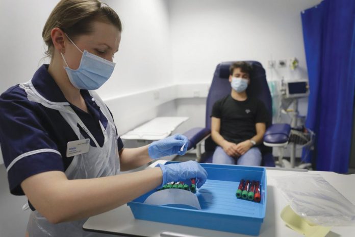 Clinical Research Nurse Aneta Gupta labels blood samples from volunteer Yash during the Imperial College vaccine trial Clinical Research Nurse Aneta Gupta labels blood samples from volunteer Yash during the Imperial College vaccine trial, at a clinic in London, Wednesday, Aug. 5, 2020. AP