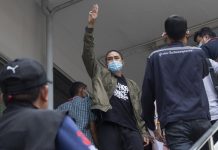 Key member of the music group Rap Against Dictatorship, Dechathorn Bamrungmuang raises a three-finger salute, a symbol of resistance, as he arrives at the Samranrat police station in Bangkok, Thailand, Thursday, Aug. 20, 2020. AP PHOTO/SAKCHAI LALIT