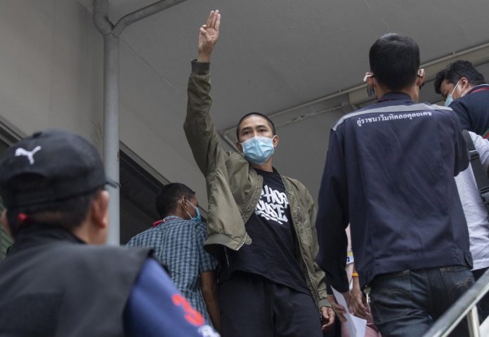 Key member of the music group Rap Against Dictatorship, Dechathorn Bamrungmuang raises a three-finger salute, a symbol of resistance Key member of the music group Rap Against Dictatorship, Dechathorn Bamrungmuang raises a three-finger salute, a symbol of resistance, as he arrives at the Samranrat police station in Bangkok, Thailand, Thursday, Aug. 20, 2020. AP PHOTO/SAKCHAI LALIT