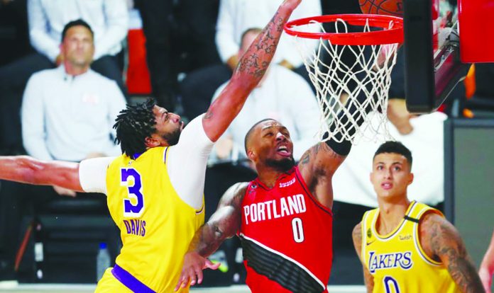 Trail Blazers Lakers Basketball Los Angeles Lakers forward Anthony Davis (3) blocks a shot by Portland Trail Blazers guard Damian Lillard (0) as Lakers forward Kyle Kuzma (0) looks on during the first half of Game 2 of an NBA basketball first-round playoff series, Thursday, in Lake Buena Vista, Florida. AP