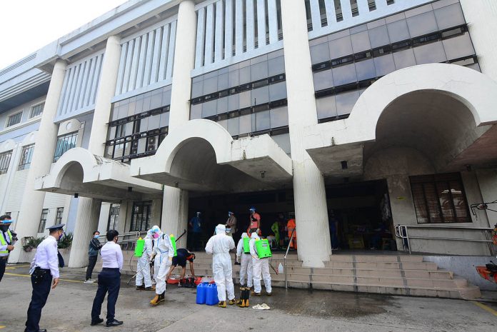 Personnel of the Iloilo City Health Office and Bureau of Fire Protection wearing protective gear as they disinfect the entrance of the Chief Justice Ramon Q. Avanceña Hall of Justice on Friday as part of the precautionary measure to stop the spread of coronavirus disease 2019. IAN PAUL CORDERO/PN