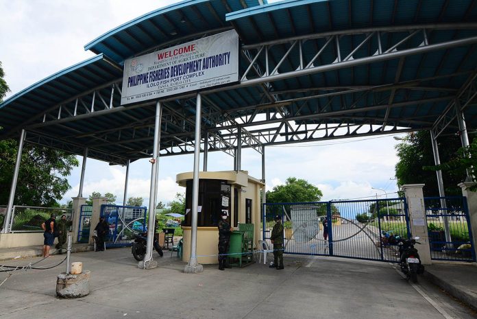 Policemen are posted at the entrance of the Iloilo Fishing Port Complex in Barangay Tanza, Iloilo City on Wednesday Policemen are posted at the entrance of the Iloilo Fishing Port Complex in Barangay Tanza, Iloilo City on Wednesday. Mayor Jerry Treñas extended the facility’s lockdown for another 72 hours after 26 more individuals got infected with coronavirus. IAN PAUL CORDERO/PN