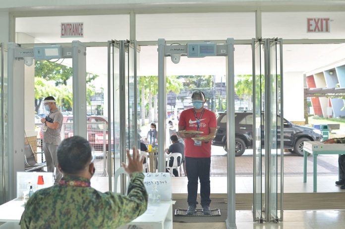 TOUGH SCREENING; A security personnel stops a man about to enter the Iloilo provincial capitol. The man must first undergo body thermal scanning. If he is feverish, he would be turned away. Aside from a temperature scan, people entering the capitol are also required to wear facemask and face shield. IAN PAUL CORDERO/ PN