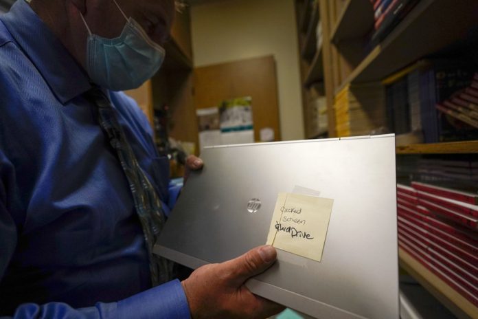 A school superintendent looks at a laptop with a cracked screen at Twentynine Palms Junior High School A school superintendent looks at a laptop with a cracked screen at Twentynine Palms Junior High School, Tuesday, Aug. 18, 2020, in California, United States. AP