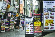 South Korea tightens distancing as cases mount People wearing face masks to help protect against the spread of the coronavirus pass by banners showing the menu items of restaurants in Seoul, South Korea, Friday, Aug. 28, 2020. AP