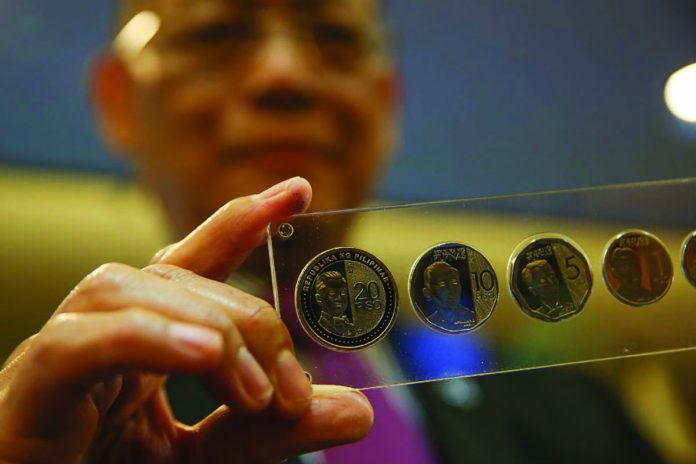 Central Bank Governor Benjamin Diokno holds new P20 and P5 coins at the Executive Business Center of the Bangko Sentral ng Pilipinas in Manila on December 17, 2019. ABS-CBN NEWS
