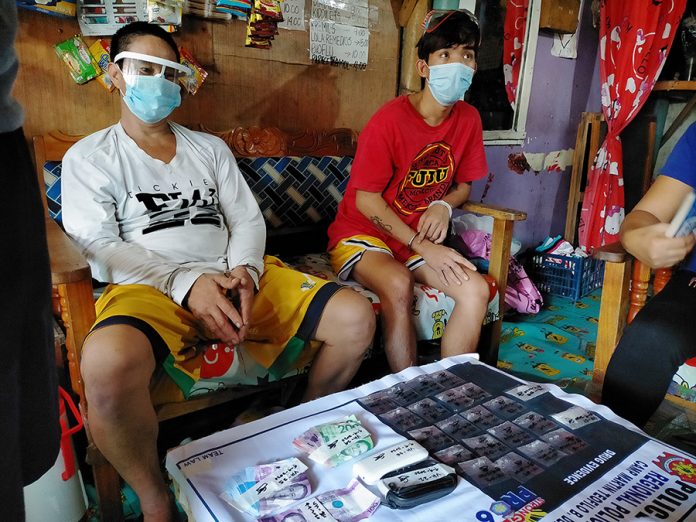 Drug suspects Vergilio Hilario, 47, and Janny Palomar, 21, sit handcuffed after they were nabbed in an entrapment operation in Barangay North Baluarte, Molo, Iloilo City on Sept. 9. IAN PAUL CORDERO/PN