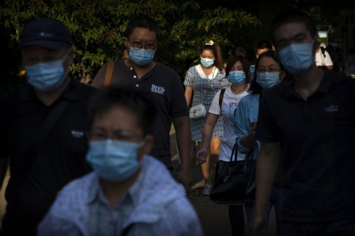 People wearing face masks to protect against the coronavirus walk along a street in the central business district in Beijing