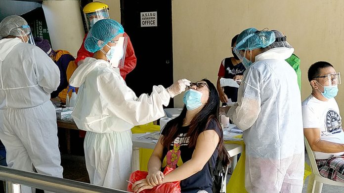 news glenda Health workers wearing protective gear extract nasal swab samples from a city government employee during the first day of mass testing at the Iloilo City Freedom Grandstand on Wednesday, Sept. 23. Panay News