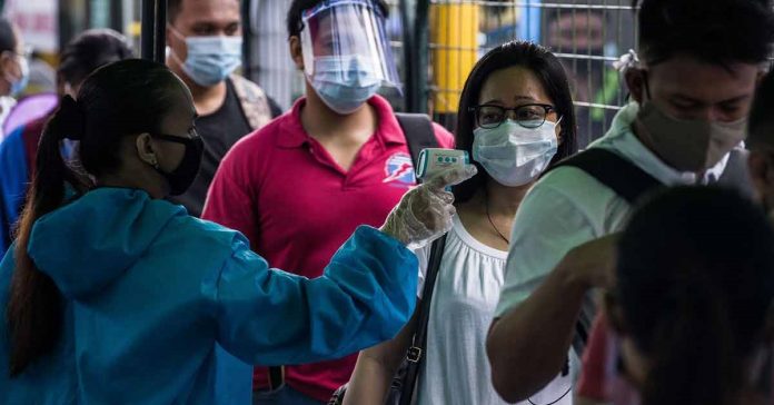 temp check A passenger has her body temperature taken before boarding a bus in Manila on July 7, 2020. AFP