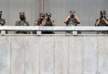 N. Korea regrets killing S. Korean to control coronavirus North Korean soldiers keep watch toward the south as South Korean Unification Minister Lee In-young inspects (not pictured) the truce village of Panmunjom inside the demilitarized zone separating the two Koreas. KOREA POOL/REUTERS