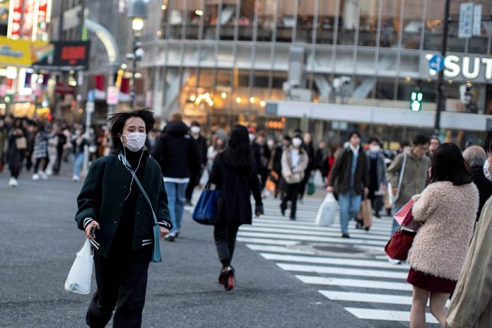 A woman wearing a protective face mask runs across a street at Shibuya in Tokyo, Japan. ATHIT PERAWONGMETHA/REUTERS