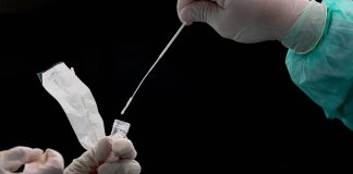 A health worker (R) puts a swab into a tube after collecting a sample for COVID-19 coronavirus testing in Gombak on the outskirts of Kuala Lumpur on April 22, 2020. (Photo by Mohd RASFAN / AFP)