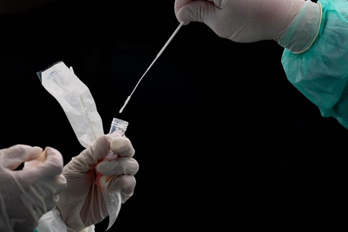 MALAYSIA-HEALTH-VIRUS A health worker (R) puts a swab into a tube after collecting a sample for COVID-19 coronavirus testing in Gombak on the outskirts of Kuala Lumpur on April 22, 2020. (Photo by Mohd RASFAN / AFP)