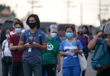 Workers wearing protective masks wait for shuttle services in Manila, Philippines. According to the Department of Labor and Employment, all employers are required to release their workers’ 13th month pay on or before Dec. 24. CNS PHOTO/ELOISA LOPEZ, REUTERS