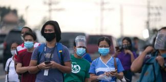 Workers wearing protective masks wait for shuttle services in Manila, Philippines. According to the Department of Labor and Employment, all employers are required to release their workers’ 13th month pay on or before Dec. 24. CNS PHOTO/ELOISA LOPEZ, REUTERS