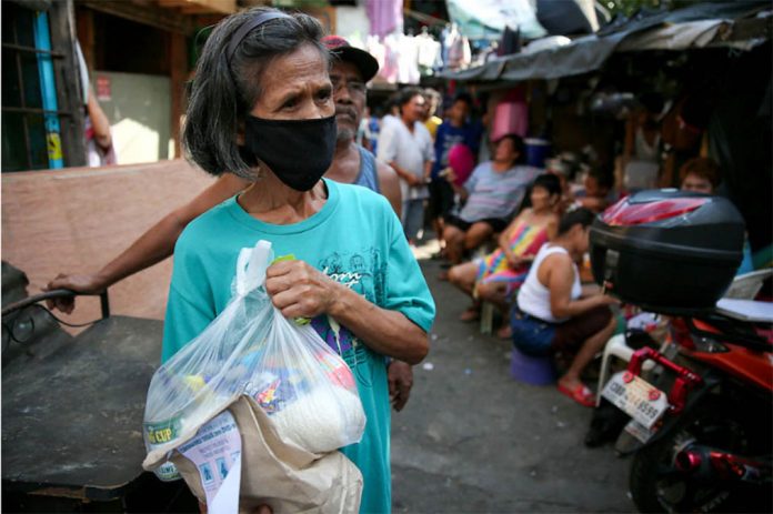 A resident of a depressed community in Quezon City receives relief goods from barangay officials on Mar. 19, 2020. FERNANDO G. SEPE JR./ABS-CBN NEWS