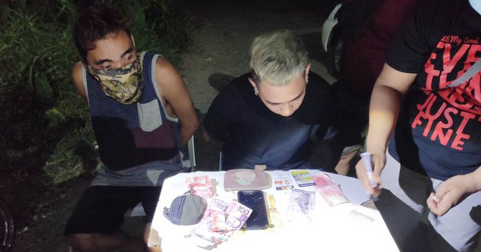 pavia buy bust Drugs suspects Welvin John Lebrilla (right) of Barangay Pandac, Pavia and his alleged cohort 30-year-old Jessie Jay Lizada of Barangay Balabag, Pavia sits handcuffed while operatives conduct an inventory of the seized illegal drugs in a buy-bust operation around 9 p.m. on Oct. 4. JIRO SHEEN EMILIO/PN