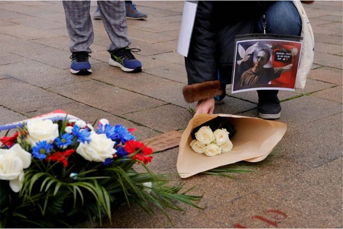 A person holding a picture of Samuel Paty, the French teacher who was beheaded on the streets of the Paris, lays flowers during a tribute in Lille, France, Oct. 18, 2020. PASCAL ROSSIGNOL/REUTERS A person holding a picture of Samuel Paty, the French teacher who was beheaded on the streets of the Paris, lays flowers during a tribute in Lille, France, Oct. 18, 2020. PASCAL ROSSIGNOL/REUTERS