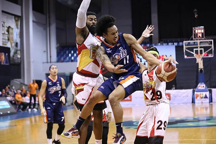 banner Meralco Bolts’ Chris Newsome looks to pass the ball after being cornered by San Miguel Beermen’s Arwind Santos and Moala Tautuaa. PBA PHOTO