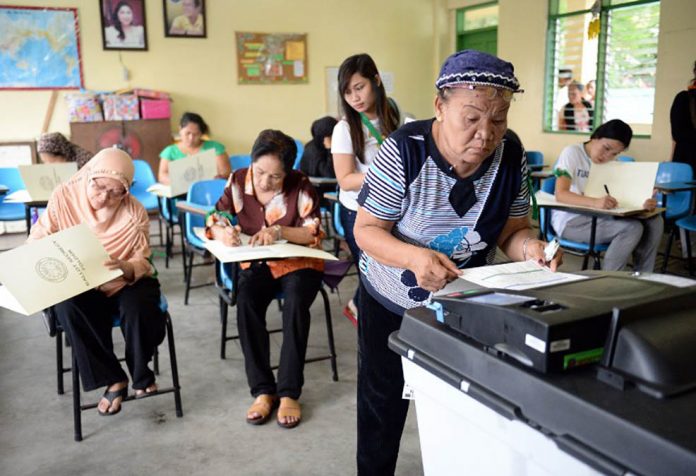 PHILIPPINES-VOTE An elderly voter places her ballot on a precinct count optical scan machine after casting her vote. TED ALJIBE/AFP
