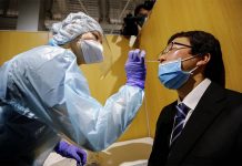 Japan opens airport coronavirus test lab for departing travellers A medical worker wearing a protective suit conducts a simulation for a polymerase chain reaction (PCR) test at newly-opened Narita International Airport PCR Center. ISSEI KATO/REUTERS