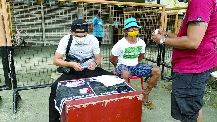 The 42-year-old Henjie Epat sits handcuffed during a drug buy-bust operation in Barangay Tagbak, Jaro, Iloilo City on Sunday. Suspected shabu valued at around P140,000 was recovered from his possession. IAN PAUL CORDERO/PN