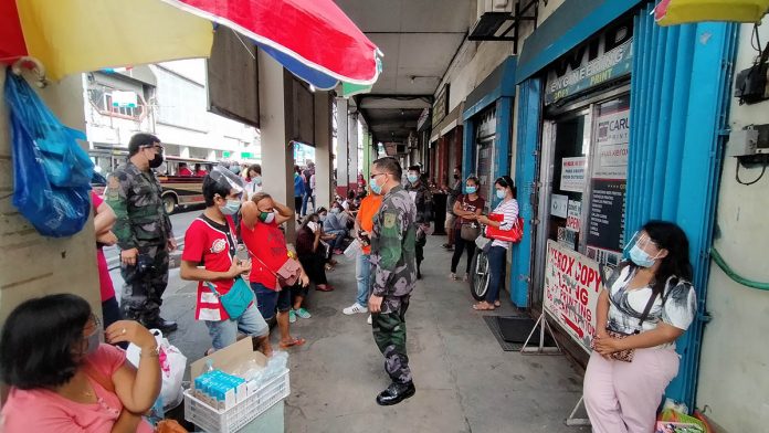 Long lines at the Philippine Statistics Authority’s regional office spill to the sidewalk of Iznart Street, Iloilo City. Police officers make sure these people follow health protocols like wearing of facemasks and physical distancing. IAN PAUL CORDERO/PN