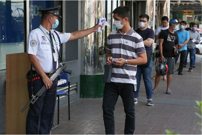 A security guard scans the temperature of clients observing social distancing as they line up to enter a bank in Quezon City. FERNANDO G. SEPE JR/ABS-CBN NEWS A security guard scans the temperature of clients observing social distancing as they line up to enter a bank in Quezon City. FERNANDO G. SEPE JR/ABS-CBN NEWS