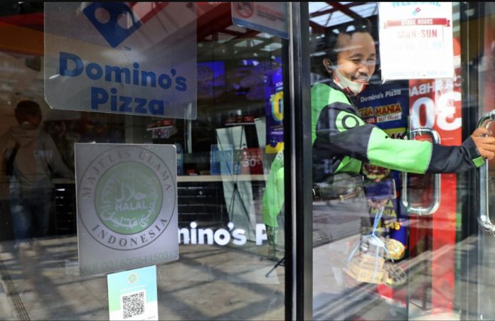 muslim A man leaves as ‘halal’ logo of Indonesian Ulema Council is displayed on the facade of a restaurant in Jakarta, Indonesia. TATAN SYUFLANA/AP PHOTO