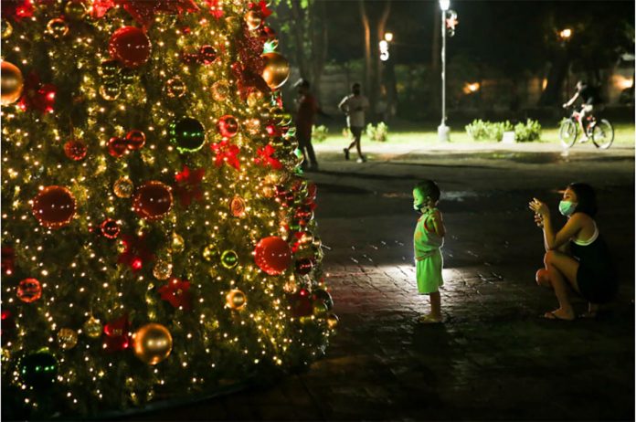 A woman takes pictures of her child in front of a giant Christmas tree at Pinaglabanan Shrine in San Juan on Dec. 10. GEORGE CALVELO/ABS-CBN NEWS