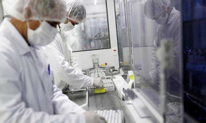 Employees handle vials containing CoronaVac, Sinovac Biotech’s coronavirus vaccine, in the bottle filling section at Butantan biomedical production center in Sao Paulo, Brazil on Jan. 12, 2021. AMANDA PEROBELLI/REUTERS