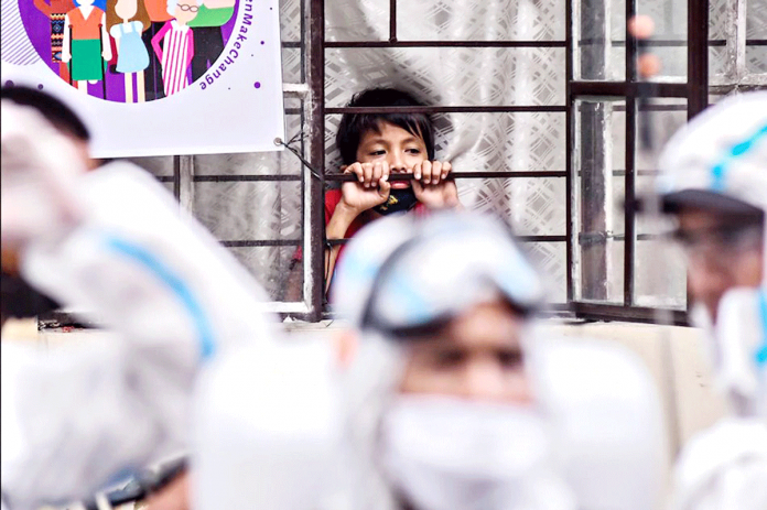A child watches as a disinfection team prepares for an operation in Barangay West Crame, San Juan City on Mar. 23, 2020. GEORGE CALVELO/ABS-CBN NEWS