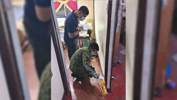 A scene of the crime operative and a police officer investigate the house of Joeffrey Parandas where he was shot to death by three unidentified assassins in Barangay Alijis, Bacolod City on Jan. 12. BCPO