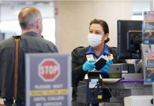 An officer wearing a face mask clears a departing passenger at Dulles International Airport. KEVIN LAMARQUE/REUTERS
