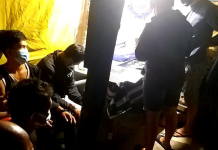 Drug suspects sit handcuffed while police officers inspect items seized from them in a buy-bust operation in Barangay Banago, Bacolod City Tuesday morning./PDEA-6 PHOTO