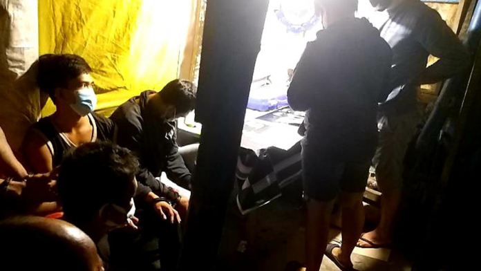 BB new Drug suspects sit handcuffed while police officers inspect items seized from them in a buy-bust operation in Barangay Banago, Bacolod City Tuesday morning./PDEA-6 PHOTO