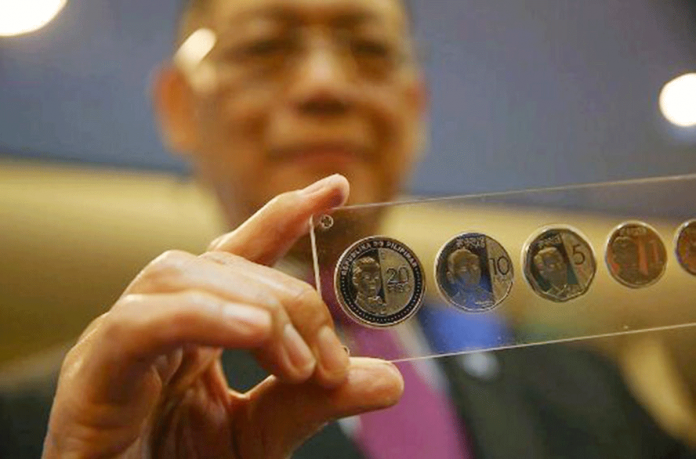 BSP Bangko Sentral governor Benjamin Diokno holds 20-piso, 10-piso, and 5-piso coins. ABS-CBN NEWS FILE PHOTO/ JONATHAN CELLONA