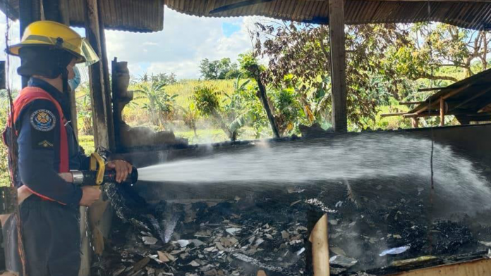 Fire for web An arson investigator attempts to put out the fire that gutted the house owned by 71-year-old Rebeca Dampong in Barangay Lawaan, Dumarao, Capiz on Thursday./BFP DUMARAO