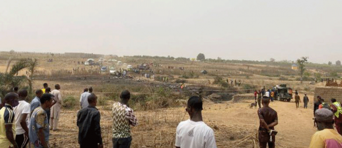 People watch as rescuers inspect the debris from a Nigerian air force plane which crashed while approaching the Abuja airport runway on Feb. 21, 2021. REUTERS/ABRAHAM ACHIRGA