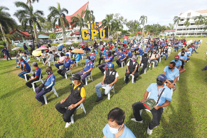 frontpic ‘FIGHT AS ONE’. Observing social distancing on the grounds of Central Philippine University in Jaro, Iloilo City, these volunteers wait for their turn to be inoculated during a recent simulation of vaccination against coronavirus disease. The city government is banking on people’s unity and cooperation to combat the pandemic. ARNOLD ALMACEN/CMO