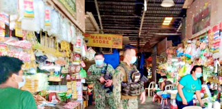 Policemen ensure compliance of vendors and residents inside the public market of Passi City on Feb. 5. Those who will be caught not wearing facemask may end up behind bars or fined. PASSI CITY LGU