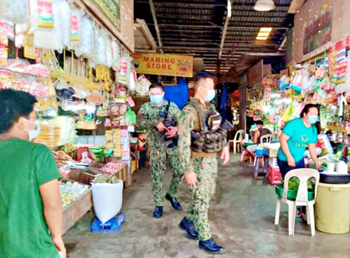 passi-pic Policemen ensure compliance of vendors and residents inside the public market of Passi City on Feb. 5. Those who will be caught not wearing facemask may end up behind bars or fined. PASSI CITY LGU