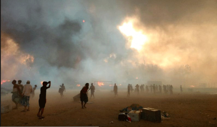 Bangladesh Refugees stand amid smoke after a fire broke out at Rohingya refugee camp in Cox's Bazar, Bangladesh, March 22, 2021. REUTERS/STRINGER/FILE