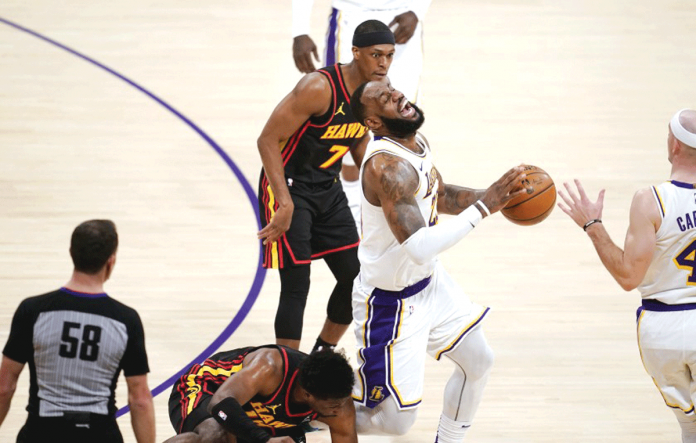 Los Angeles Lakers star LeBron James grimaces as Atlanta Hawks forward Solomon Hill (7) crashed to his right leg during a loose-ball scramble. MARCIO JOSE SANCHEZ/ASSOCIATED PRESS